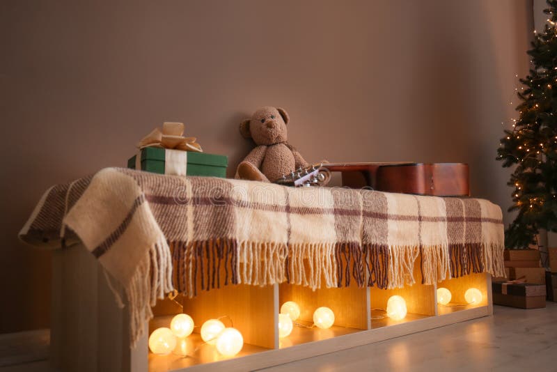 Shelf unit with glowing Christmas garland and gifts in living room