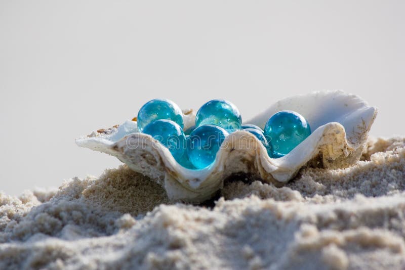 Shell with glass pebbles on sand