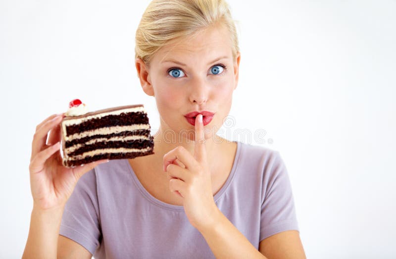 Shh, dont tell anyone - Diets. Young woman holding a slice of chocolate cake and gesturing secrecy.