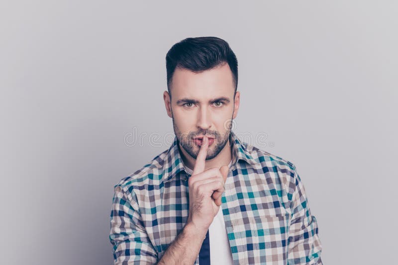 Shhh! Portrait of attractive man with bristle in checkered shirt holding finger on mouth showing hush silence sign, guy asking for silence, standing over grey background. Shhh! Portrait of attractive man with bristle in checkered shirt holding finger on mouth showing hush silence sign, guy asking for silence, standing over grey background