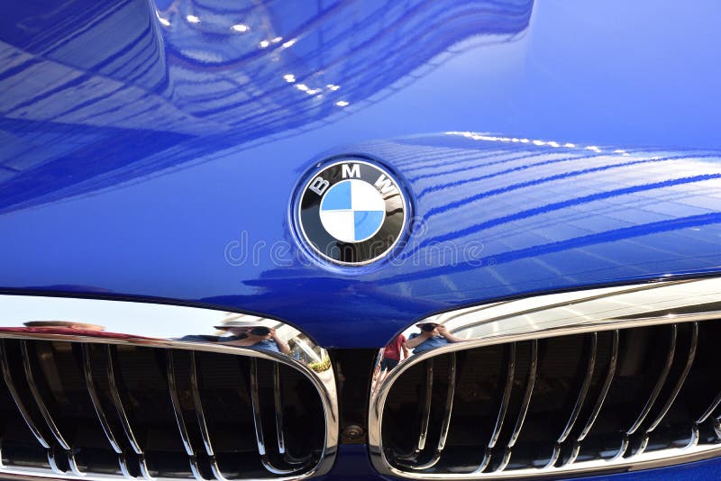 Shiny `BMW` emblem on a blue car hood with chrome grill stock images Shiny `BMW` emblem on a blue car hood with chrome grill stock images