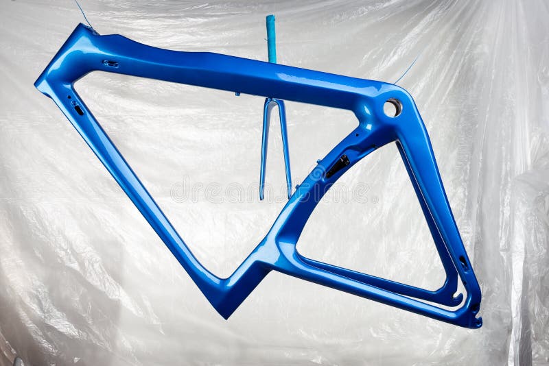 Shiny new fresh fresh paintwork coating paint of a metallic blue carbon racing road bicycle frame set with fork in front of paint