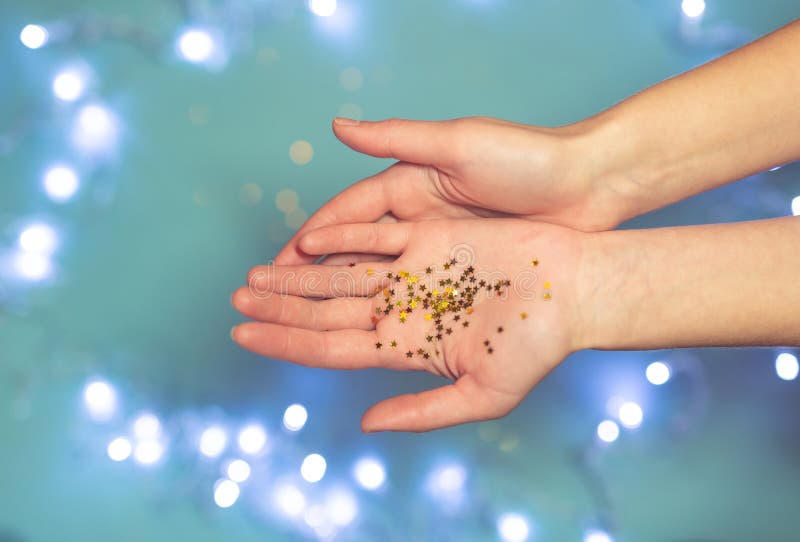 Shiny tiny golden stars in open human palms on a blue background with bokeh. stock photos Shiny tiny golden stars in open human palms on a blue background with bokeh. stock photos