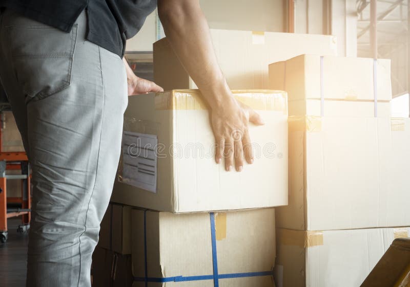 Shipment boxes. Warehouse worker lifting cardboard boxes stack on pallet rack. Cargo export. Distribution warrehousing. stock photography