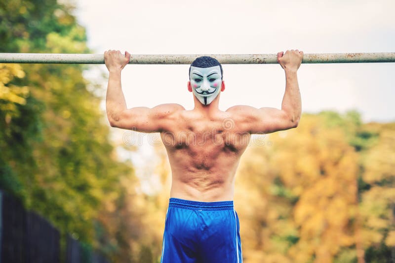 Shirtless handsome man doing chin ups in park, wearing an anonymus mask. Fitness player, personal trainer working out in park royalty free stock images Shirtless handsome man doing chin ups in park, wearing an anonymus mask. Fitness player, personal trainer working out in park royalty free stock images