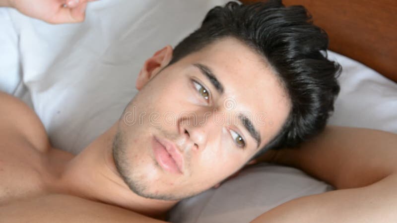 Shirtless sexy mannelijk model die alleen op zijn bed liggen