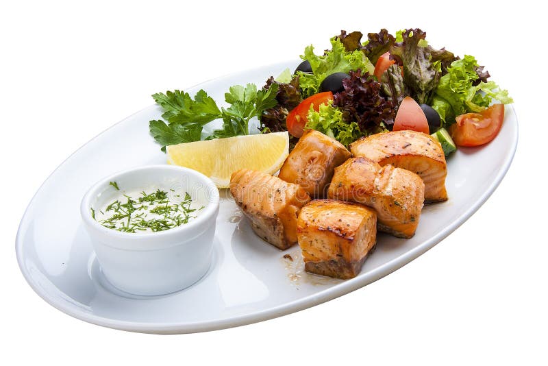 Shish kebab from salmon with vegetables and salad. On a white plate