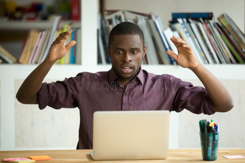 Shocked african american office worker looking at laptop screen.