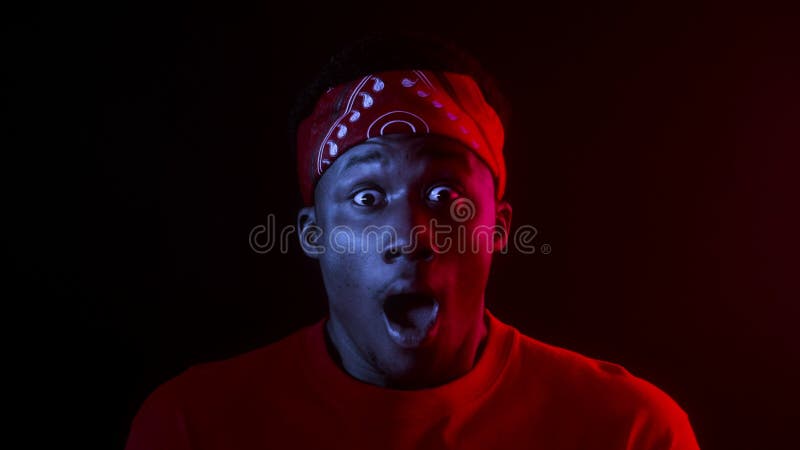 Shocked African Man Opening Mouth Standing In Dark Studio