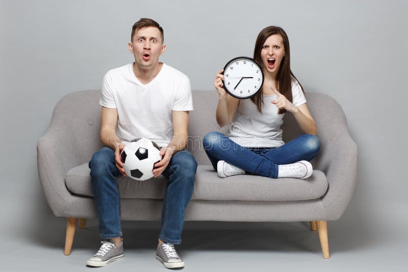 Shocked angry couple woman man football fans in white t-shirt cheer up support favorite team with soccer ball, holding