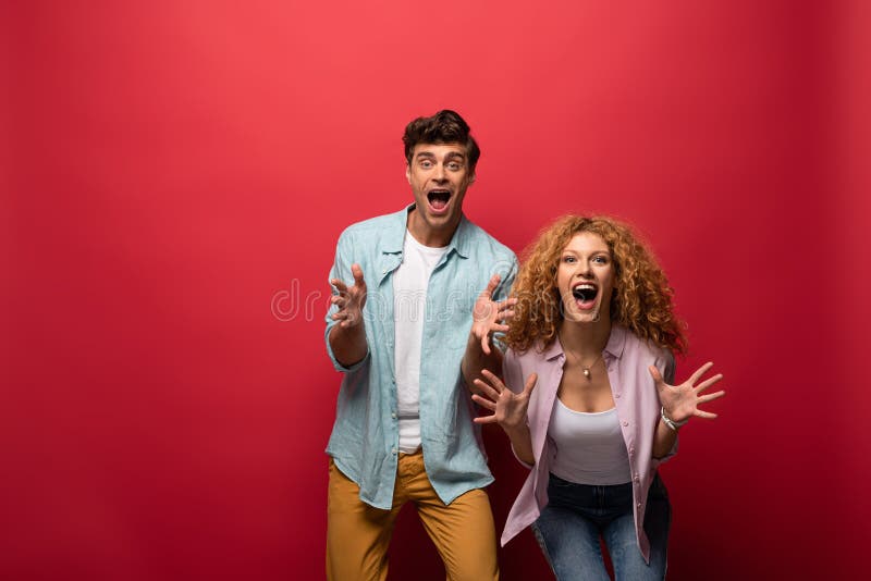 Shocked couple screaming and gesturing, isolated on red stock image