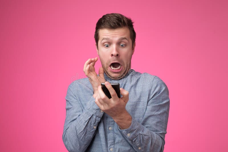 Young man standing, using smartphone and watching video with amazed face. stock photography Young man standing, using smartphone and watching video with amazed face. stock photography