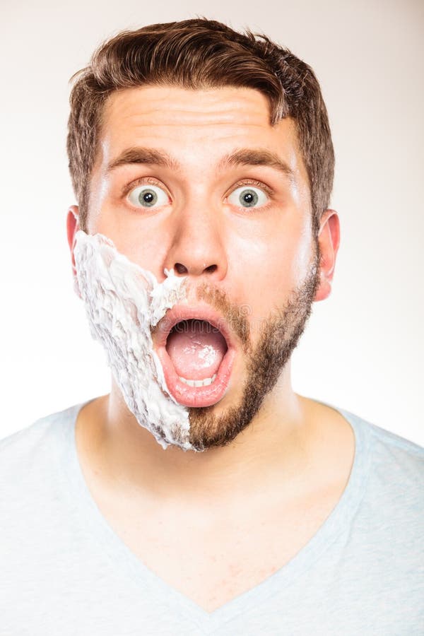 Shocked man with shaving cream foam on half face. 