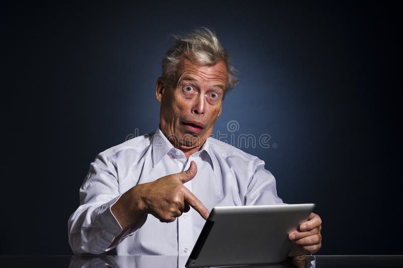 Shocked senior man pointing to his tablet