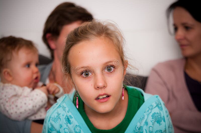 A teen girl with a shocked look on her face with her family on the background. A teen girl with a shocked look on her face with her family on the background.