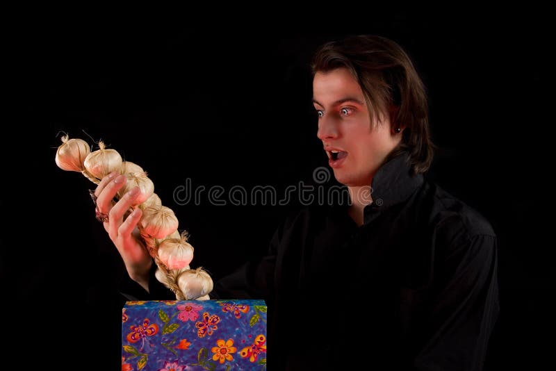 Shocked vampire with gift box taking out garlic stock photos