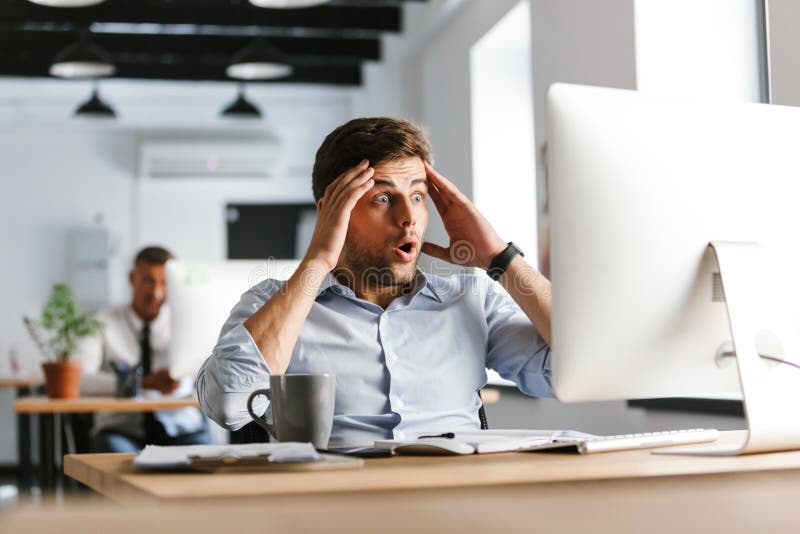 Shocked verwirrte den männlichen Manager, der compuer verwendet und Kopf hält stockfotografie
