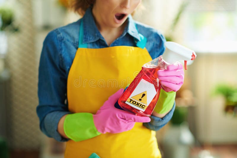 Closeup on shocked woman with spray bottle of cleaning supplies reading instruction in the house in sunny day. Closeup on shocked woman with spray bottle of cleaning supplies reading instruction in the house in sunny day