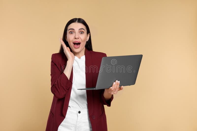 Shocked woman with laptop on beige background royalty free stock image