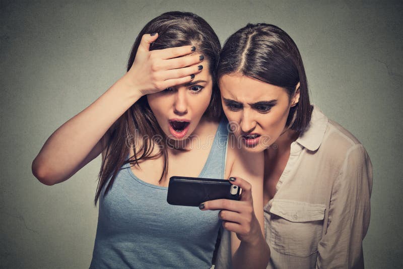 Shocked women displeased young girls looking at mobile phone