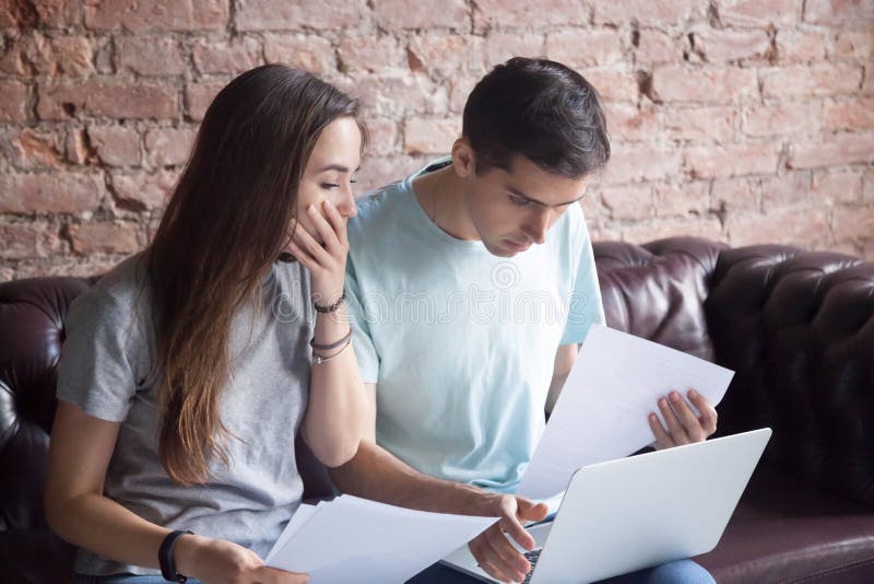 Shocked young couple looking at documents and laptop. stock photos