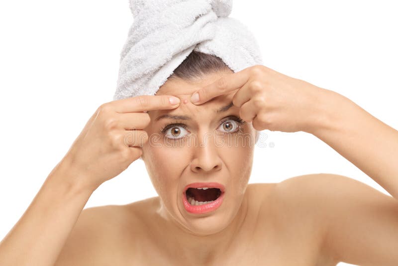 Shocked young woman squeezing a pimple on her forehead