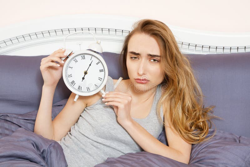 Shocked young woman waking up with alarm, overslept work, bad sleep insomnia. Girl hold clock when lying on bed in the morning stock images Shocked young woman waking up with alarm, overslept work, bad sleep insomnia. Girl hold clock when lying on bed in the morning stock images