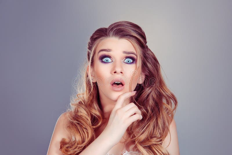 Shocking news. Beautiful shocked surprised curly blonde woman girl with big eyes with open month looking at camera on a royalty free stock image Shocking news. Beautiful shocked surprised curly blonde woman girl with big eyes with open month looking at camera on a royalty free stock image