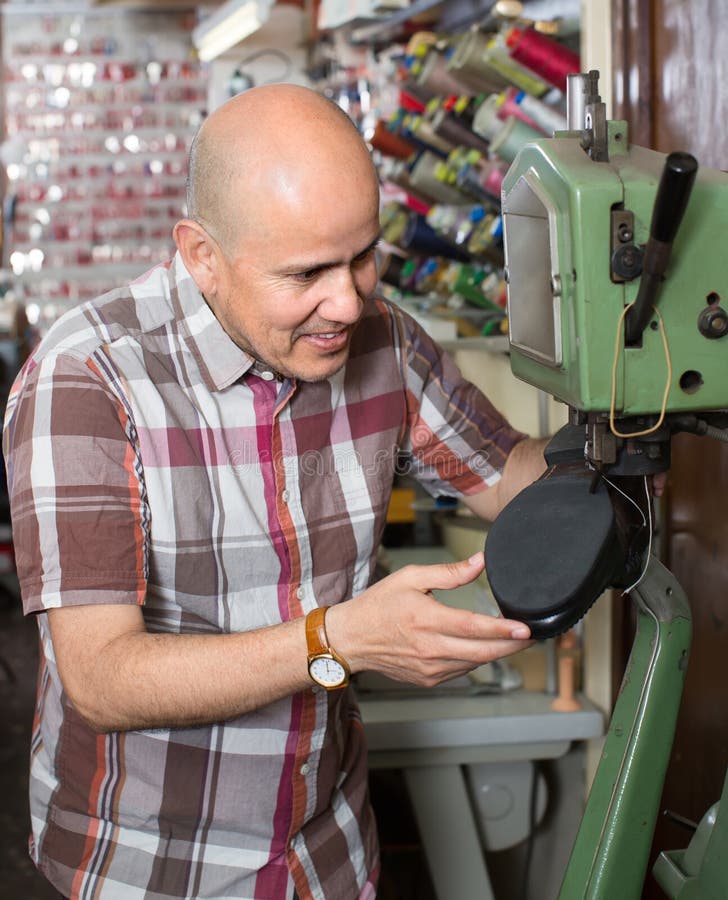 Maduro reparador de coser calzado sobre el máquina en zapato estudio.