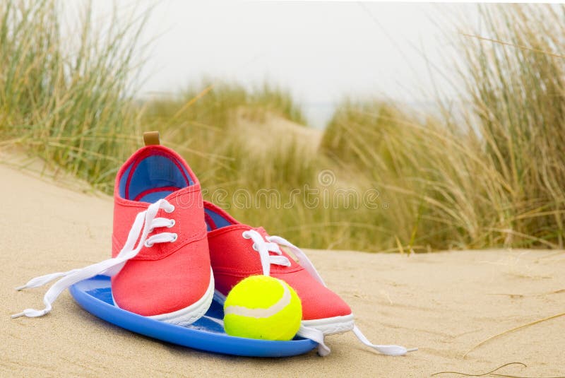 Shoes, ball and frisbee on beach landscape