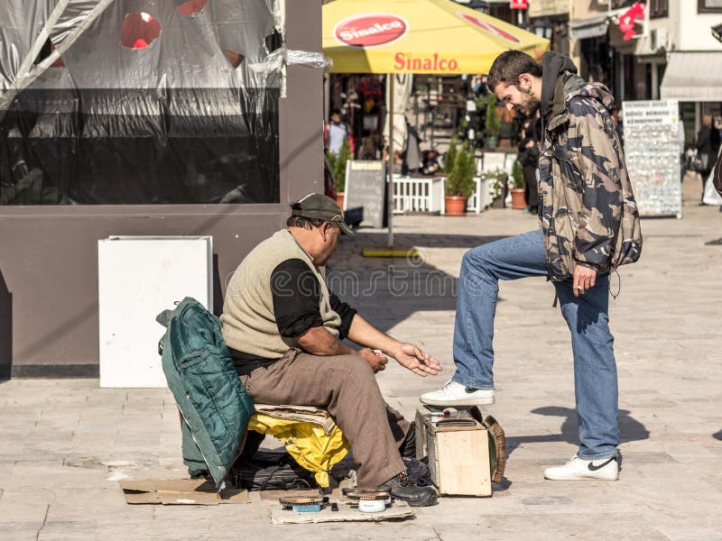 Shoeshiner polishing the shoes of a white young man in the Skopje bazar in the capital city of Macedonia royalty free stock photography Shoeshiner polishing the shoes of a white young man in the Skopje bazar in the capital city of Macedonia royalty free stock photography
