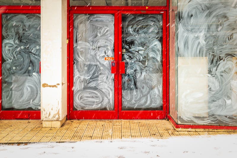 Shop front entrance door of closed down business under winter snow during covid lockdown in england uk
