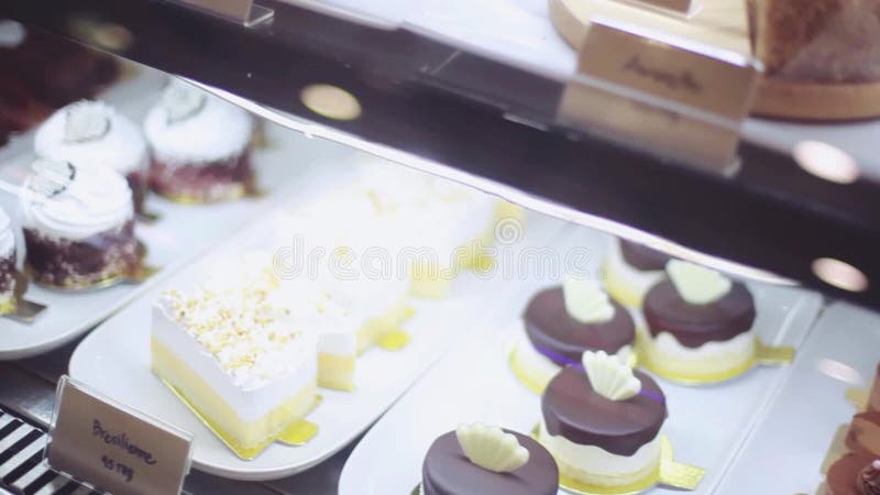 Shop window in a bakery or grocery shop with wide choice or range of various deserts with beautiful blurred bokeh on