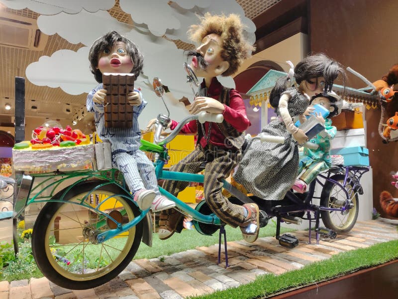 A shop window with several bright cartoon dolls riding a bicycle together in various poses. A shop window with several bright cartoon dolls riding a bicycle together in various poses