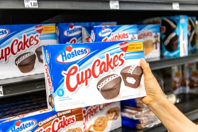 Shoppare räcker att rymma en packe av lyxfnasket som MUFFIN brännmärker glaserade chokladkakor med krämig fyllning arkivbild Shoppare räcker att rymma en packe av lyxfnasket som MUFFIN brännmärker glaserade chokladkakor med krämig fyllning arkivbild
