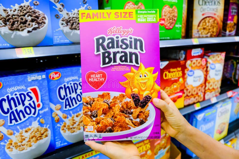 Shoppers hand holding a package Kellogg`s Brand Raisin bran flakes cereal for sale