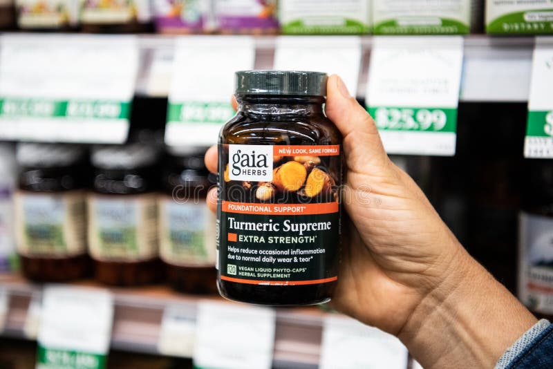 Shoppers hand holding a plastic bottle of Gaia Herbs Brand Turmeric vegan liquid phyto caps