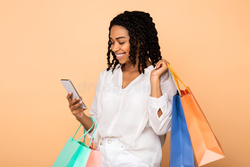 Happy African Girl Using Cellphone Holding Shopper Bags, Studio Shot