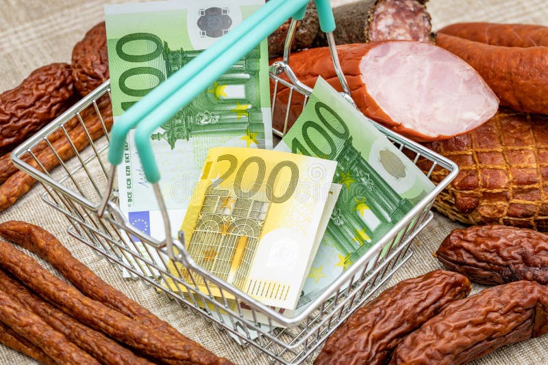 Shopping basket with Euro money around meat products, sausages and cold cuts, the concept of inflation, rising prices and more