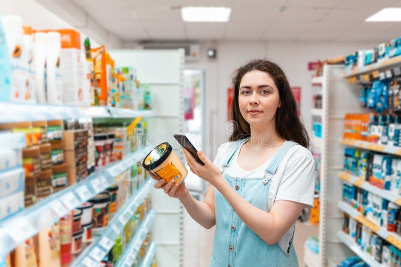 Shopping. A beautiful young woman scans the composition of the body cream. Modern technology in everyday life royalty free stock photos Shopping. A beautiful young woman scans the composition of the body cream. Modern technology in everyday life royalty free stock photos