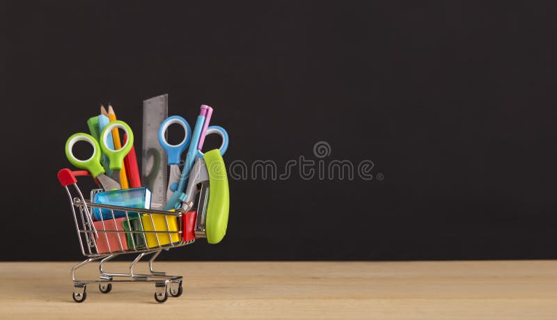 Shopping cart with school supplies over chalkboard background