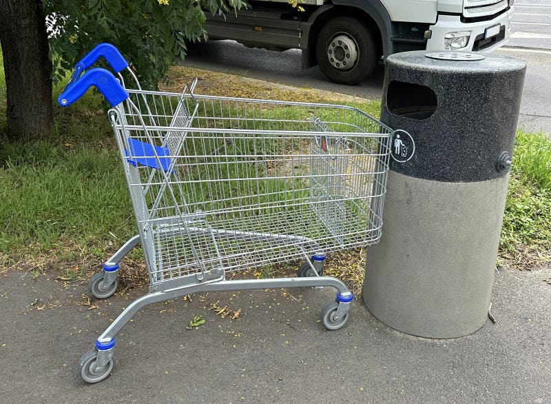 Shopping cart on the street next to a trashcan royalty free stock photography
