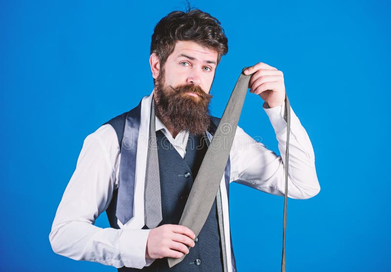 Shopping for necktie. Hipster shopping the latest tie collection. Shop assistant offering broad assortment of neckties for shopping. Bearded shopper choosing necktie in shopping mall.