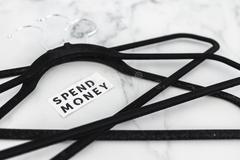 Shopping and purchasing power, group of clothes hangers with Spend Money text in the middle concept of buyers reducing their stock image Shopping and purchasing power, group of clothes hangers with Spend Money text in the middle concept of buyers reducing their stock image