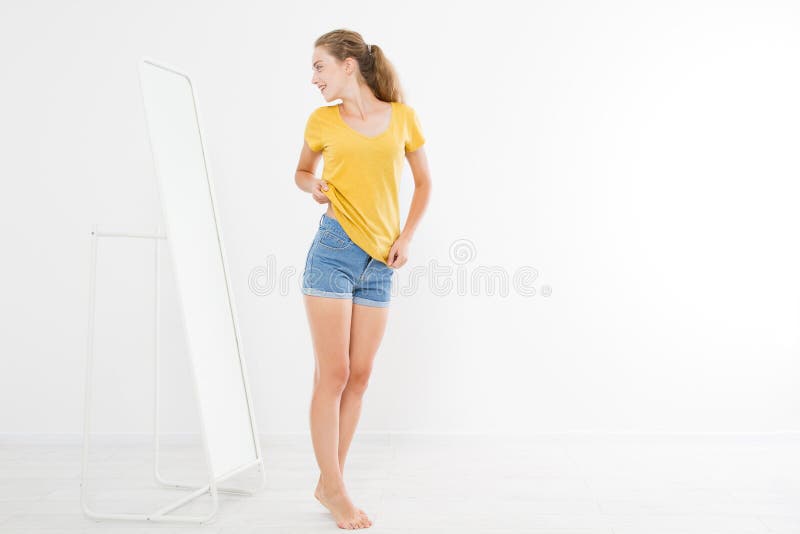 Shopping sale concept. Blonde girl in jeans and t shirt. Young woman in good body shape looking at mirror and lose weight. royalty free stock photography Shopping sale concept. Blonde girl in jeans and t shirt. Young woman in good body shape looking at mirror and lose weight. royalty free stock photography