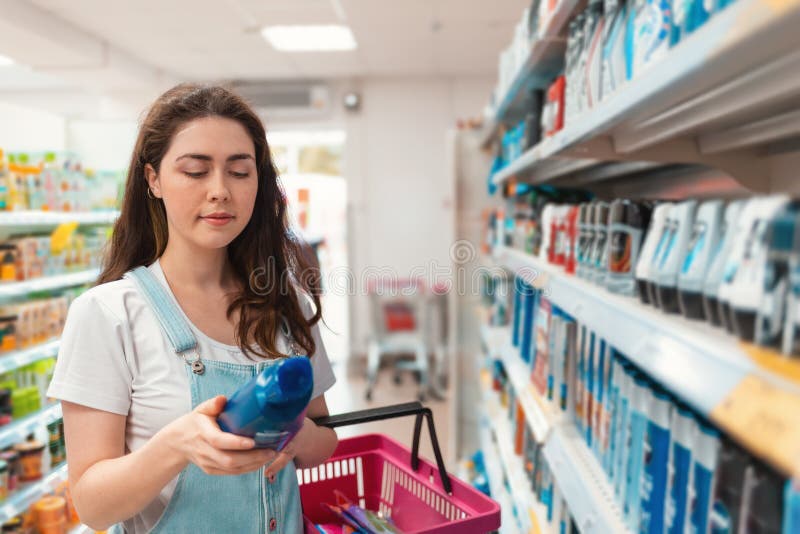 shopping Ung härlig kvinna som läser en etikett av schampo i lagret