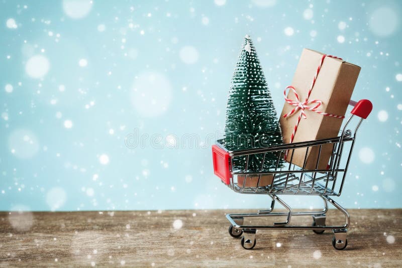 Shoppingvagn med gåva- eller gåva- och granträdet på snöig effektbakgrund Jul och försäljningsbegrepp för nytt år greeting lyckli royaltyfri fotografi