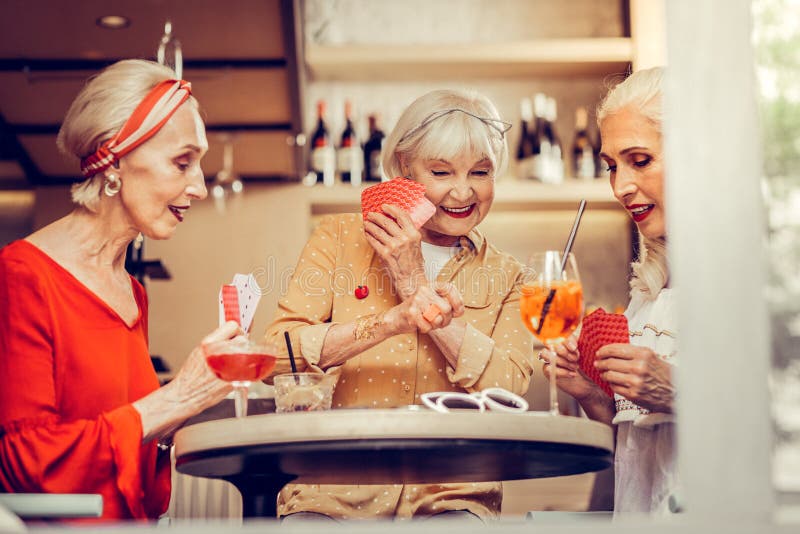 Short-haired smiling woman hiding her card from friends royalty free stock photo Short-haired smiling woman hiding her card from friends royalty free stock photo