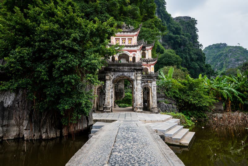 Premium Photo  Lone tourist with traditional vietnamese hat at bich dong  pagoda entrance gate, ninh binh vietnam, buddhist temple set amid jungle  and karst mountain range. traveling alone, keep social distancing.