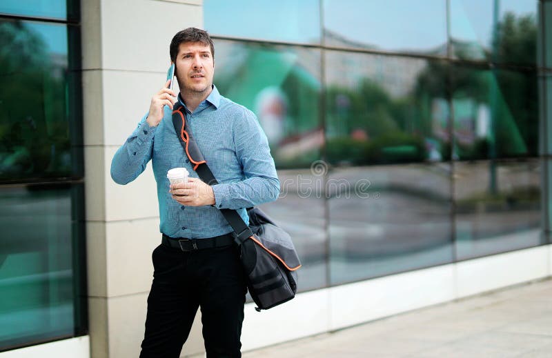 Shot of a handsome commuter taking a phone call while walking outside an office building stock images Shot of a handsome commuter taking a phone call while walking outside an office building stock images